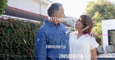 Mature couple embracing on sunlit backyard patio with futuristic data grid overlay