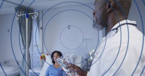 Senior doctor holding IV bag beside patient in hospital ward for clinical care