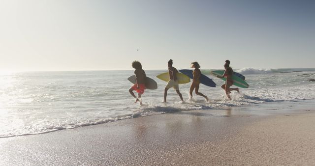 Diverse women and men running to the sea with surfboards form beach. Summer, free time, friendship, vacation.