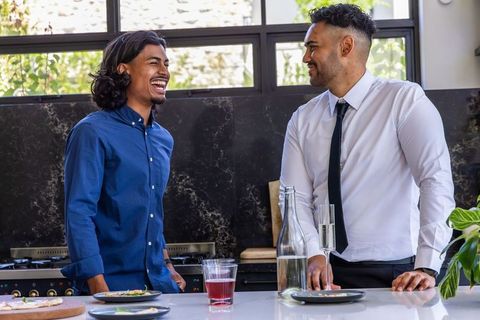 Laughing african american colleagues chatting at modern kitchen island