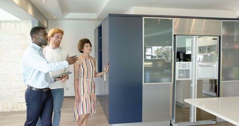 Diverse couple touring modern kitchen with real estate agent