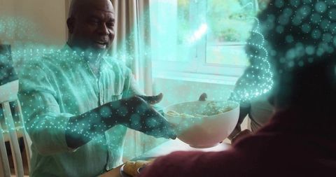 Senior man sharing bowl in tech-enhanced family gathering