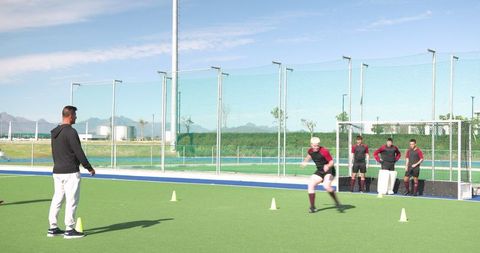 Athletes Executing Cone Drill Outdoors with Coach