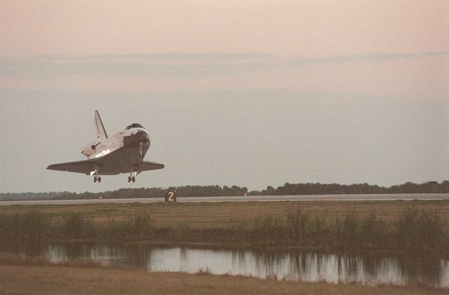 Picture depicts the Space Shuttle Endeavour landing just after sundown at Kennedy Space Center's Shuttle Landing Facility Runway 33. This image is rich in historical significance, indicating the completion of the STS-99 mission and featuring notable figures in the space community. Ideal for use in educational materials, presentations on space exploration, NASA activities, or aviation history.
