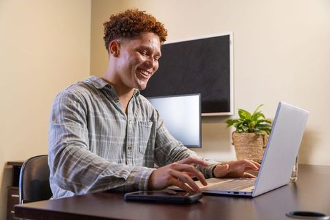 Smiling Professional Typing on Laptop in Modern Office