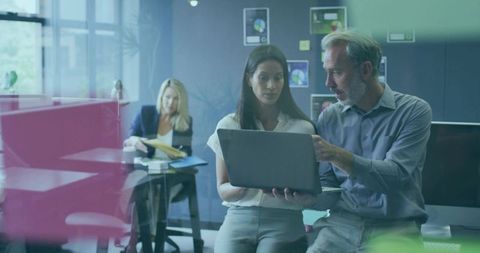 Colleagues Collaborating on Laptop Task in Modern Office