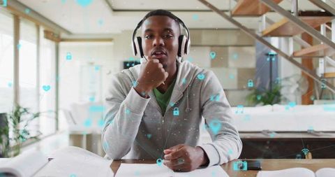 Young Man with Headphones Studying Online at Home Desk