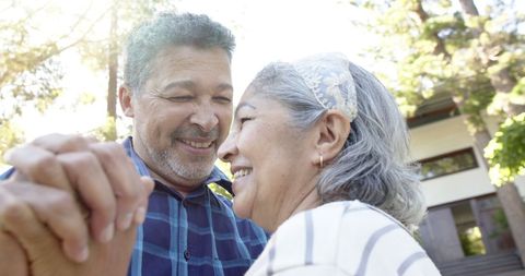 Senior Couple Joyfully Dancing in Sunlit Garden Outdoors