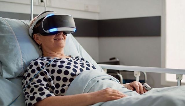 Senior woman exploring virtual reality while reclining in hospital bed with medical monitor