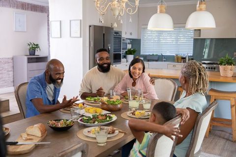 Family Enjoys Meal Around Kitchen Table with Salad and Lemonade