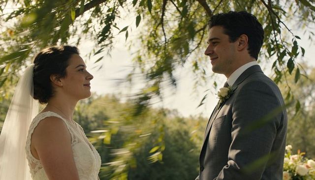 Bride and groom gazing under willow branches during romantic outdoor wedding ceremony