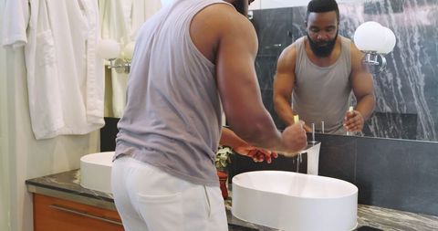 African American Man Washing Hands in Stylish Modern Bathroom