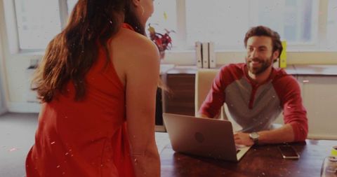 Presenting rising sales chart on laptop while collaborating with smiling colleague