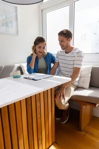Couple Reviewing Documents in Cozy Kitchen Nook During Daytime