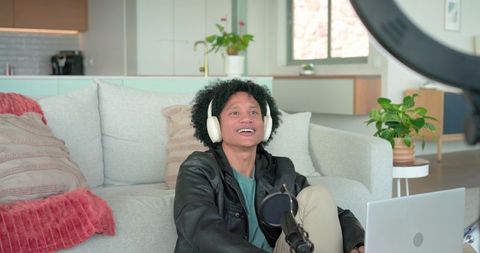 African american creator recording podcast at home wearing headphones and leather jacket