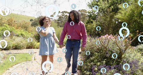 Couple walking hand in hand through garden with augmented reality social network icons