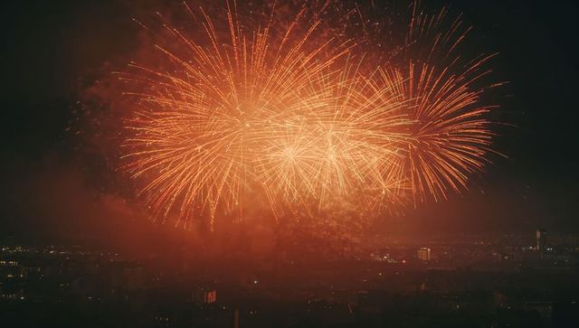Vibrant orange-golden firework display over cityscape