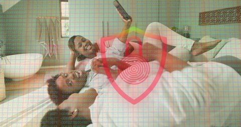 Three friends taking selfie on bed with smartphone and digital privacy shield overlay