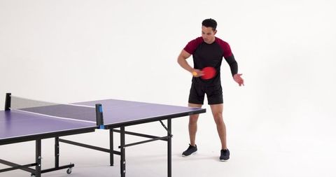 Hispanic male practicing table tennis in minimalist studio