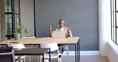 Man Conducting Virtual Meeting on Laptop in Modern Office