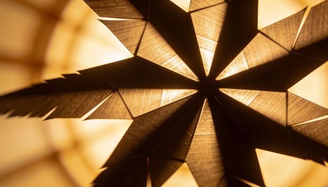 Glowing star lantern casting sharp geometric shadows and warm ambient backlighting