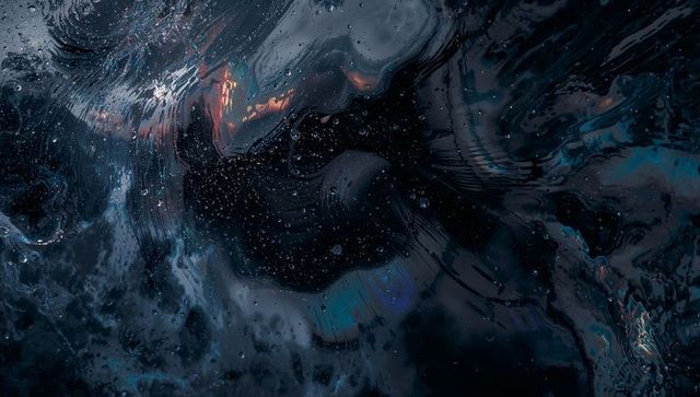 Dark iridescent liquid swirl with shimmering droplets and micro bubbles