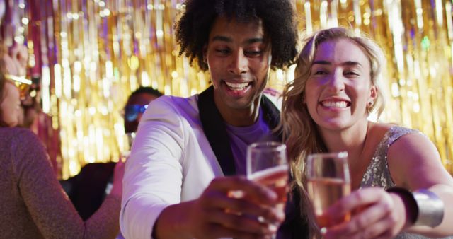 Image of happy diverse couple dancing holding glasses of champagne at a nightclub. Fun, drinking, going out and party concept.