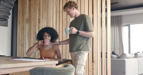 Couple enjoying morning coffee while reviewing paperwork at cozy modern wood dining table