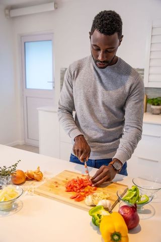 Man Chopping Tomatoes in Modern Kitchen Preparing Fresh Meal