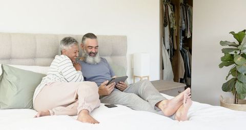 Senior Couple Relaxing on Bed with Tablet and Smartphone