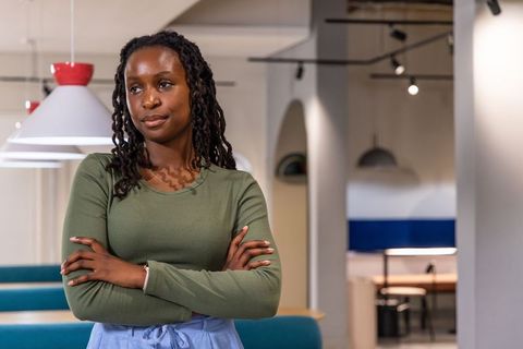 Confident african american woman standing arms crossed in modern coworking lounge