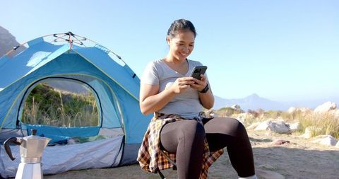 Smiling Woman Enjoying Camping Trip with Tent and Mountain Views