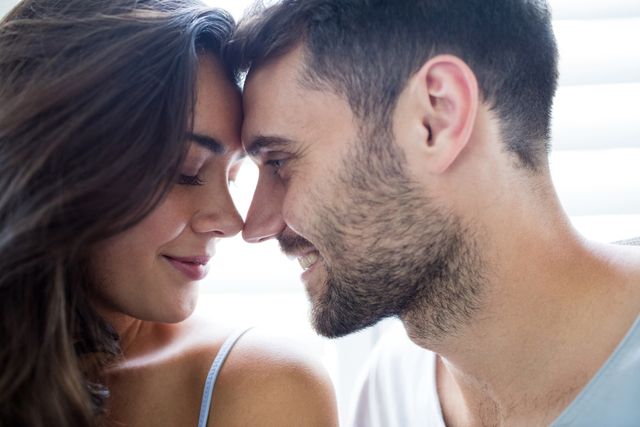 Young couple sharing an intimate moment, touching foreheads and smiling. Perfect for romantic, relationship, or emotional bonding concepts. Can be used in advertisements, social media campaigns, and articles about love and affection.