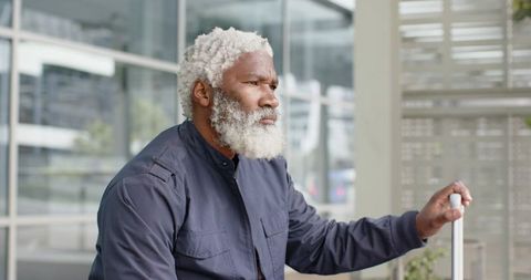 Senior African American Traveler Waiting at Modern Terminal Holding Luggage Handle