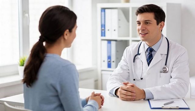 Smiling male doctor consulting female patient during medical appointment