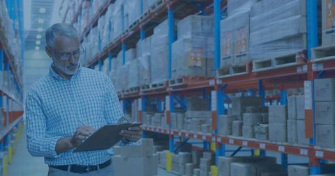 Senior warehouse manager conducting inventory audit with clipboard among pallet racking