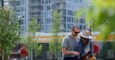 Young Couple Sharing Exciting Moments on Smartphone in Urban Cityscape