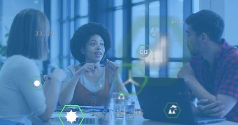 Young professionals collaborating around laptop, presenting data overlays and teamwork