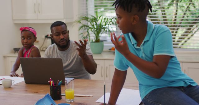 African american father using laptop and helping his son with homework at home. family, togetherness and happiness concept
