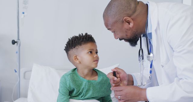 This image depicts a kind pediatrician interacting with a young boy in a hospital bed. The boy looks pensive while the doctor is showing care and concern. Ideal for promoting pediatric care, healthcare services, children's hospitals, and medical education materials.