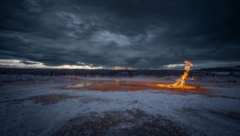 Flaming geothermal vent in snowy landscape at sunset