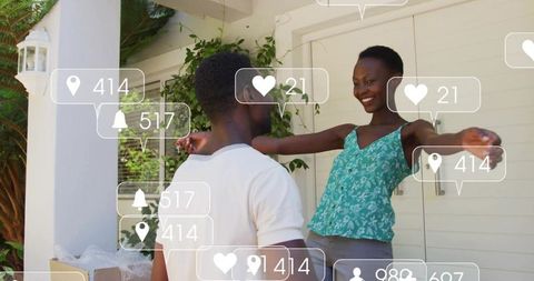 Couple reuniting with open-arm hug on porch amid delivery boxes and social notifications