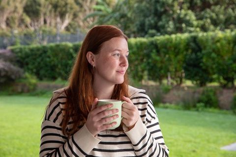 Redheaded Woman Relaxing with Mug in Green Garden Setting