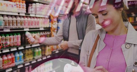 Young woman reading label while shopping refrigerated beverages in bright supermarket aisle