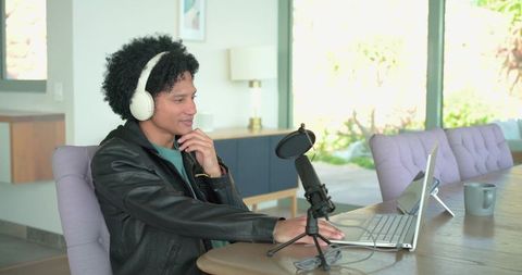African american podcaster recording in sunlit modern home with laptop and microphone