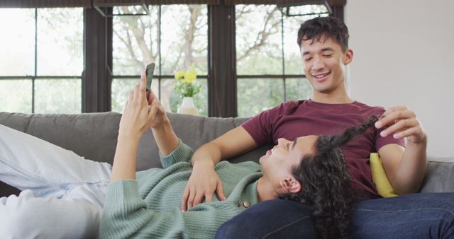 Couple Relaxing on Sofa, Woman Browsing Phone, Man Playing with Her Hair - Download Free Stock Images Pikwizard.com