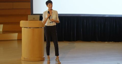 Young businesswoman presenting on stage at conference event