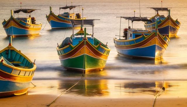 Colorful wooden fishing boats mooring at golden hour with warm sea reflections