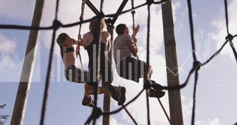 Group of friends climbing ropes on adventure course at sunset