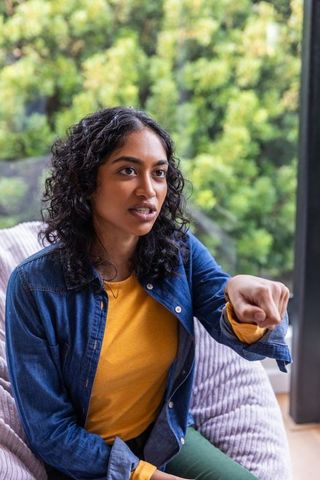 South Asian Woman Relaxing Indoors, Gesturing While Seated